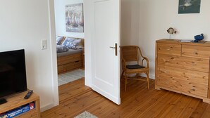 A room with a bed, a television, a dresser, and a chair. - Apartment Heimsoth Kappeln EG - Apartments Heimsoth in Kappeln (Kappeln)