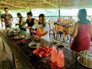 A buffet table with various dishes and drinks, surrounded by people. - Dstino Río Amazonas Casa Rústica (Iquitos)