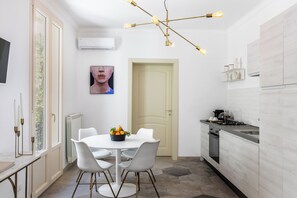 Une cuisine moderne avec des meubles blancs, une table à manger avec des chaises et un lustre.