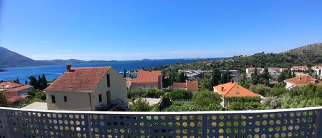 A coastal town with terraced houses, a clear blue sea, and a hilly backdrop.