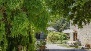 A stone building with a garden, outdoor seating, and a gravel path. - Holiday apartment with outdoor pool and WiFi (Cortona)