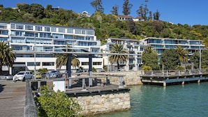 A waterfront hotel with multiple floors, a dock, and lush greenery.