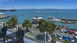 A marina with boats, a parking area, and a view of the sea and mountains.