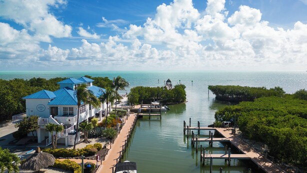 A coastal hotel with a dock, clear blue sky, and calm sea.