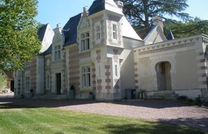 A large, historic building with a symmetrical facade, multiple chimneys, and a central entrance with a decorative archway. - Spacious lodging in Touraine, 8 ppl, private garden, tranquility (Le Boulay)