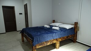 A bedroom with a wooden bed, a blue bedspread, and white pillows. - Nomad - Hostel (Bishkek)