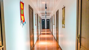 A long, narrow hallway with doors on both sides, a wooden floor, and wall-mounted decorations. - Nomad - Hostel (Bishkek)