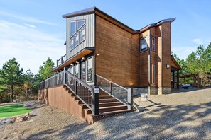 Une maison moderne à deux étages, avec une façade en bois, un balcon et un escalier menant à l’étage supérieur.