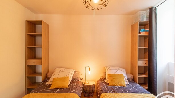 A twin bedroom with two beds, a bedside table, a lamp, and built-in shelving on either side. - Charming Riverside Home in UNESCO Heritage Village with Modern Amenities & Near Angers (Bouchemaine)