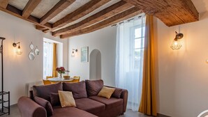 Ein Wohnzimmer mit braunen Sofas, einem Esstisch mit gelben Stühlen und einer Küchenzeile im Hintergrund.
