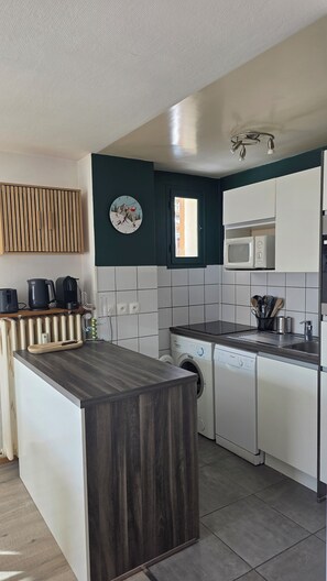 A modern kitchen with a central island, built-in appliances, and a view to the outside. - Beautiful apartment of 53m² located in the heart of the resort for 6/8 people (Les Deux Alpes)