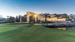 A large, well-lit building with a pool and a golf course in the foreground.