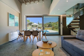 A modern living room with a dining area, a sofa, and a staircase.
