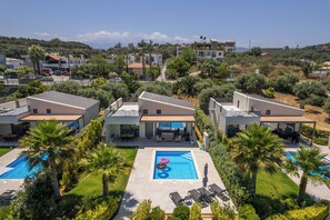 A modern hotel with multiple swimming pools, a covered outdoor area, and a view of the surrounding landscape.