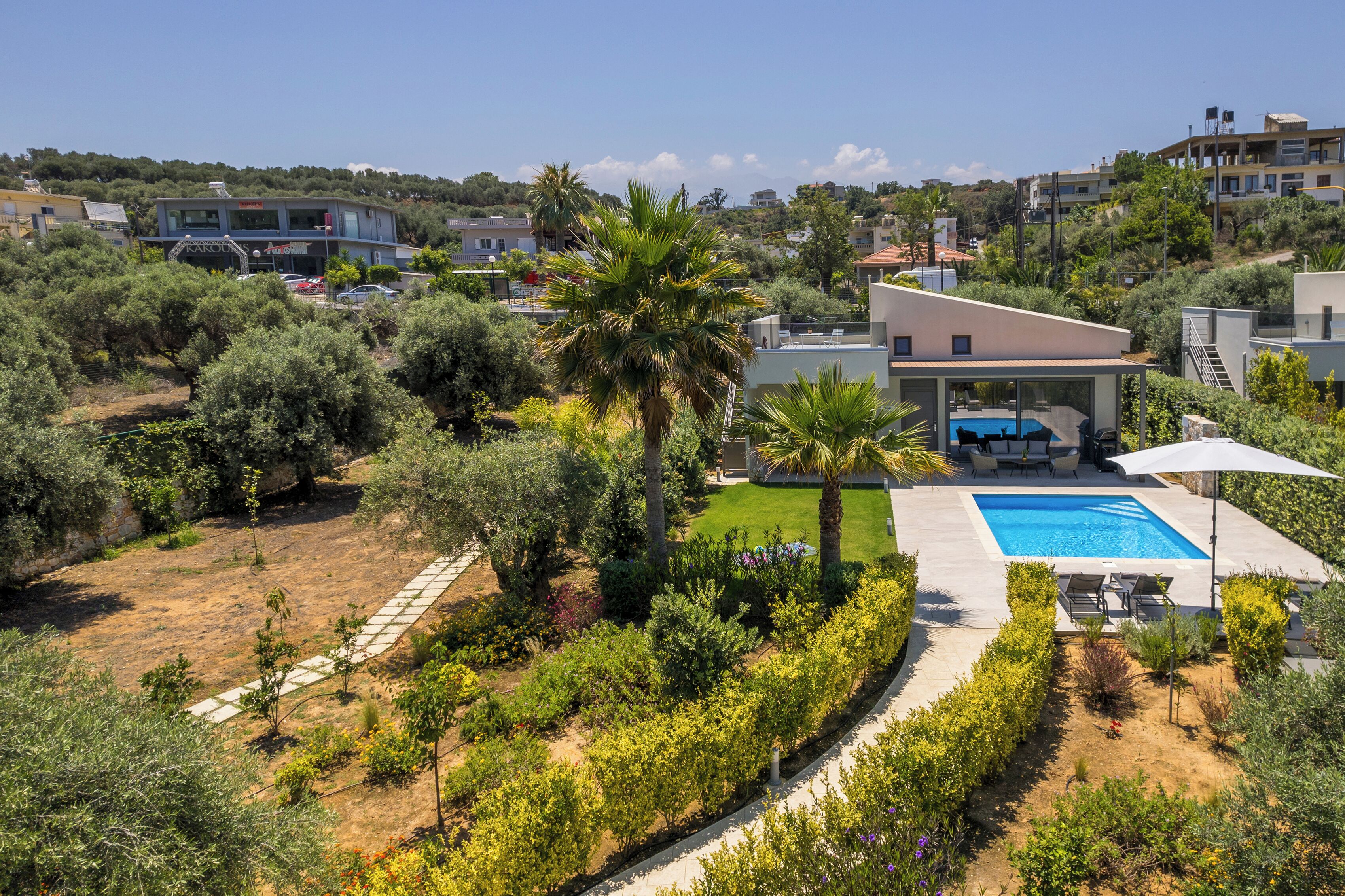 En moderne villa med swimmingpool, overdækket terrasse og anlagt have.