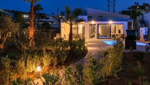 A modern house with a swimming pool, surrounded by lush greenery and palm trees. - Heated Private Pool★Brand New Lux villa★Walk to ALL★BBQ (Chania)