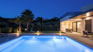A modern outdoor pool area with a patio, seating, and a well-lit building. - Heated Private Pool★Brand New Lux villa★Walk to ALL★BBQ (Chania)