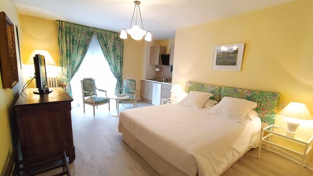 Hotellihuone, jossa on suuri sänky, työpöytä, tuoli, pieni keittonurkkaus ja ruokailutila.