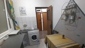 Una cocina compacta con lavadora, tendedero y una pequeña mesa de comedor.