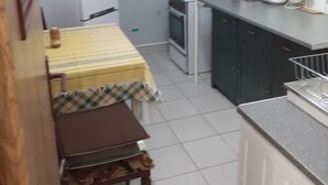 Cocina compacta con una mesa de comedor, un mueble pequeño y un microondas.