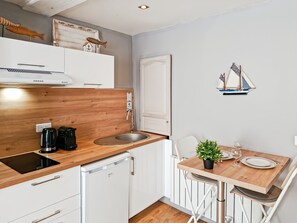 A compact kitchen with a wooden countertop, a built-in dishwasher, and a small dining area with a table and chairs. - Le studio de la Ferté - In the heart of Saint Valery's main street (Saint-Valery-sur-Somme)