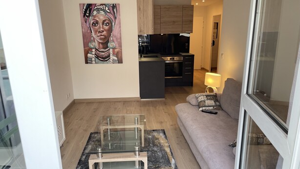 A modern living room with a glass coffee table, a beige sofa, and a painting on the wall. - Very attractive, fully-furnished, luxury T2 apartment 5 minutes' walk from the center. (Divonne-les-Bains)