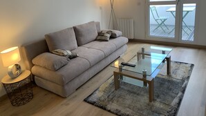 A modern living room with a sofa, a glass coffee table, a lamp, and a view of the outside. - Very attractive, fully-furnished, luxury T2 apartment 5 minutes' walk from the center. (Divonne-les-Bains)