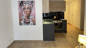 A modern kitchen with wooden cabinets, a black countertop, and a built-in oven. - Very attractive, fully-furnished, luxury T2 apartment 5 minutes' walk from the center. (Divonne-les-Bains)