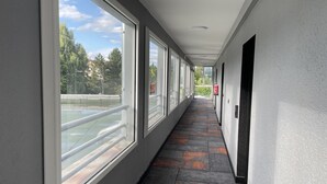 A corridor with large windows, a tiled floor, and a fire extinguisher on the wall. - Very attractive, fully-furnished, luxury T2 apartment 5 minutes' walk from the center. (Divonne-les-Bains)