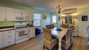 A kitchen with white cabinets, a microwave, an oven, and a dining area with wicker chairs and a table.