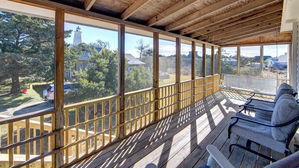A covered outdoor deck with wooden railings and a bench.