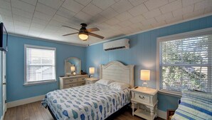 A bedroom with a bed, bedside tables, a ceiling fan, and a window with blinds.