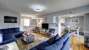 A living room with a sofa, TV, and a dining area with chairs and a table. - Saltwater Therapy - Ocracoke Island (Ocracoke)