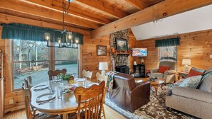 A cozy cabin interior with a dining area, a fireplace, a television, and a comfortable seating area. - CEDAR KNOB - 2 bdrm/2 bath, screened patio, wood fireplace (Townsend)