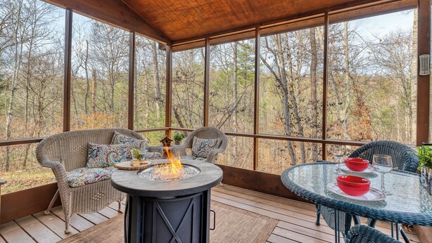 A covered outdoor deck with wicker furniture, a glass table, and a fire pit. - CEDAR KNOB - 2 bdrm/2 bath, screened patio, wood fireplace (Townsend)
