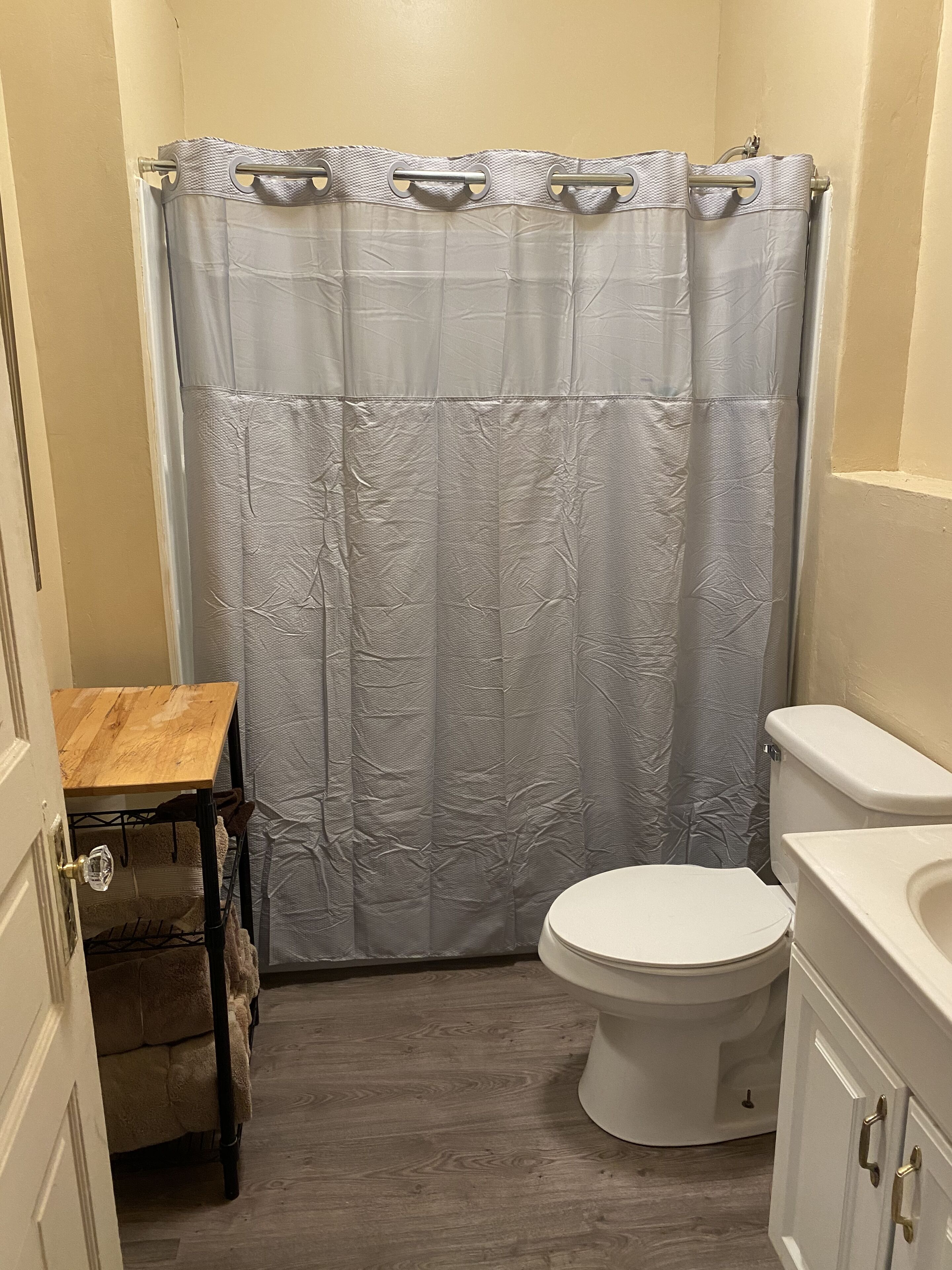 Ein Badezimmer mit Toilette, einem Holzwaschtisch und einer Duschvorhang.