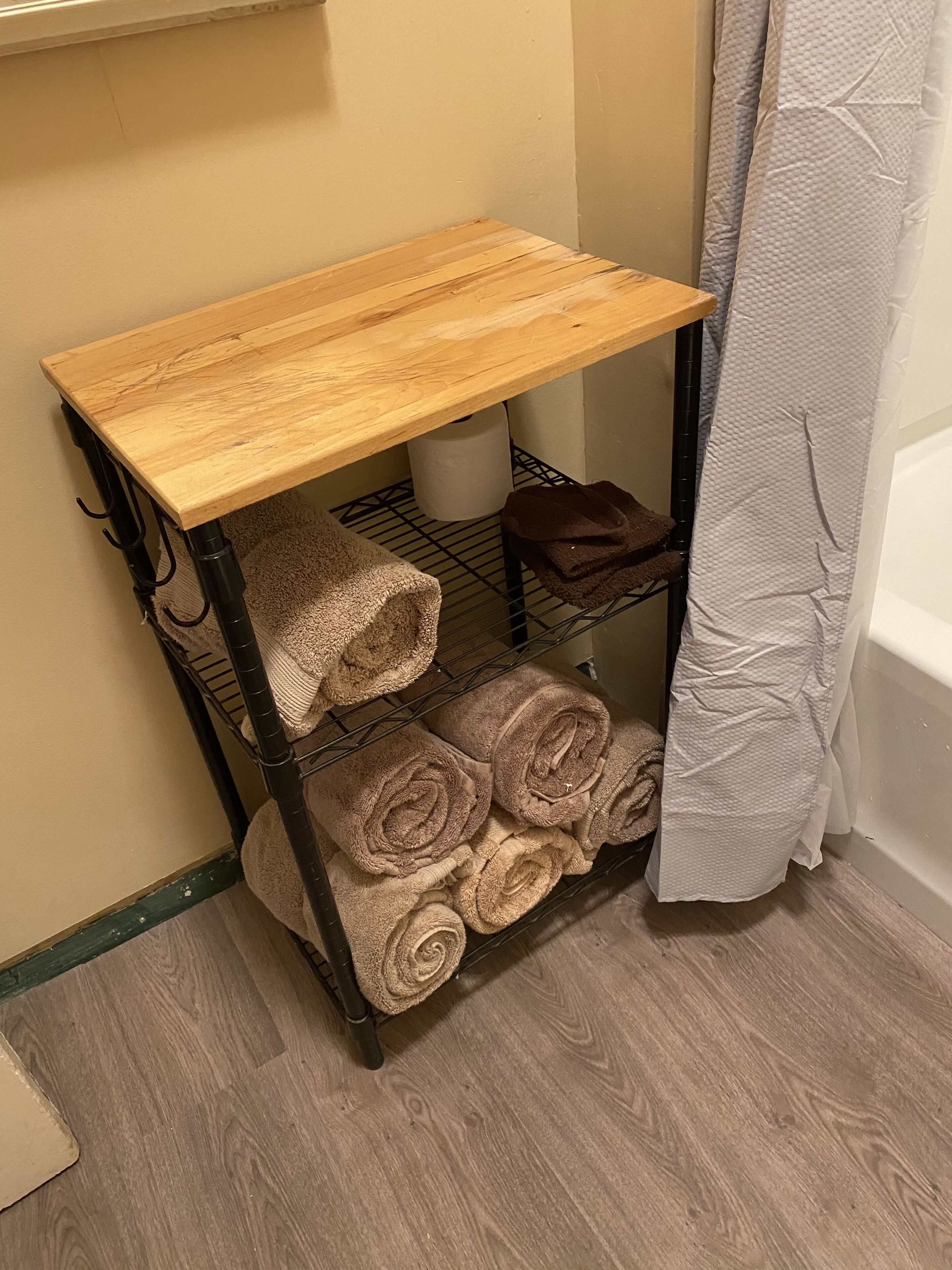 Une étagère en bois avec des serviettes et un rouleau de papier toilette.