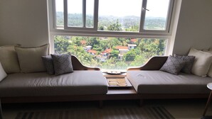 Una habitación con sofá cama frente a una ventana que ofrece vistas a una zona residencial.