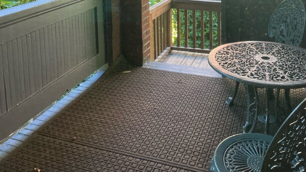 Eine überdachte Terrasse mit Tisch und Stühlen, einem hängenden Korb und einer Satellitenschüssel.