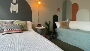Ein modernes Schlafzimmer mit einem großen Bett, einem kleineren Sofa, einer Hängeleuchte und einer Wand mit abstrakten Mustern.