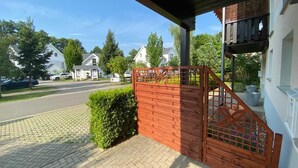 A residential property with a wooden gate, a paved driveway, and a white house with a balcony.