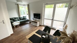 A modern living room with a sofa, TV, and dining area.