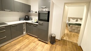 A modern kitchen with grey cabinets, a built-in oven, and a coffee maker.