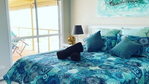 A bedroom with a large bed, a window with a view, and a painting on the wall. - Stunning beachfront view ,  (North Beach)