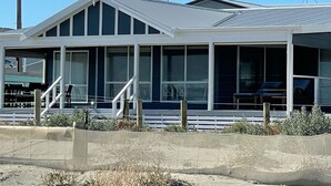 A modern two-story house with large windows, a covered porch, and a visible staircase. - Stunning beachfront view ,  (North Beach)