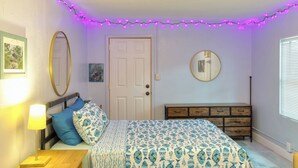 Quarto com cama, cômoda, espelho e luzes de fada.