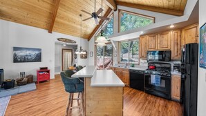 A modern kitchen with wooden cabinets, a central island, and a ceiling fan. - Mountain View: Gorgeous Views, AC, Jacuzzi bathtub! (Idyllwild)