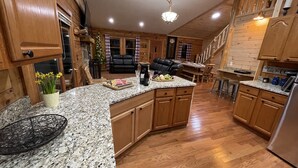 Eine geräumige Küche mit Granit-Arbeitsplatten, Holzschränken und einer zentralen Kochinsel.