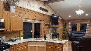 Eine Küche mit Holzausstattung, einer Granitabdeckung, einem Kamin, einem Fernseher und einem Weihnachtsbaum.
