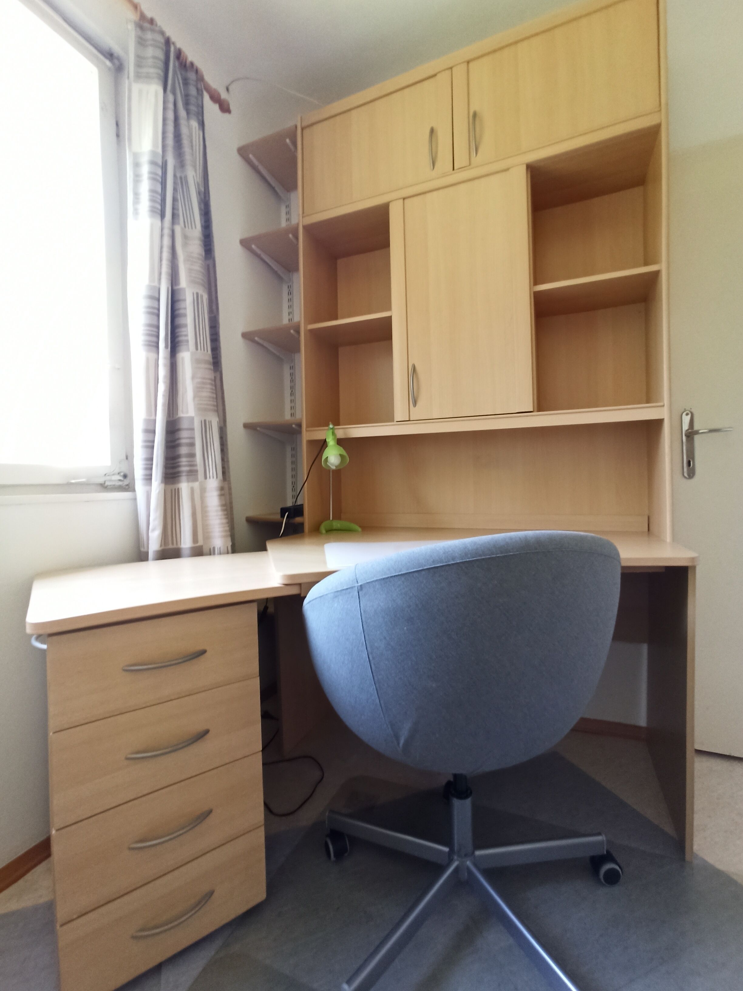 Una sala de estudio con escritorio, silla y estantería.
